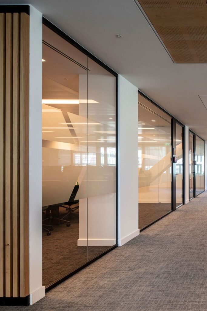 Black frame glass partitioning with room booking systems and book ended with wood slats